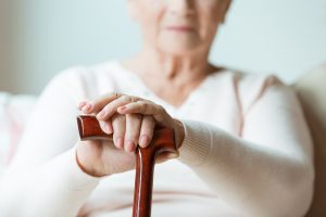 Mulher idosa sofrendo com dores da artrose sentada com o apoio de uma bengala, Casa de repouso em são paulo
