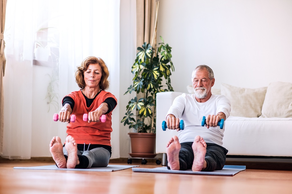 casal de idosos praticando exercícios dentro de casa