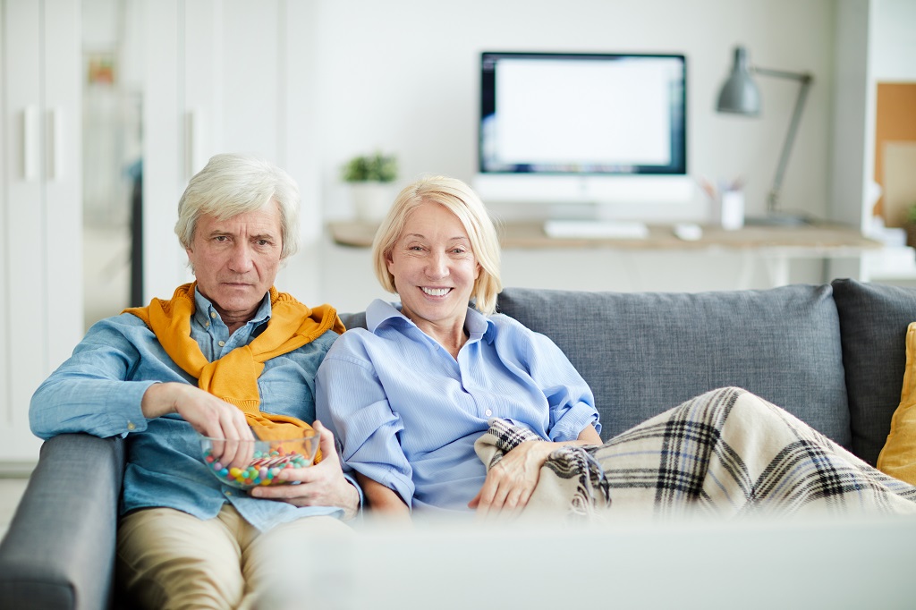 casal sentado no sofá assistindo filmes para idosos
